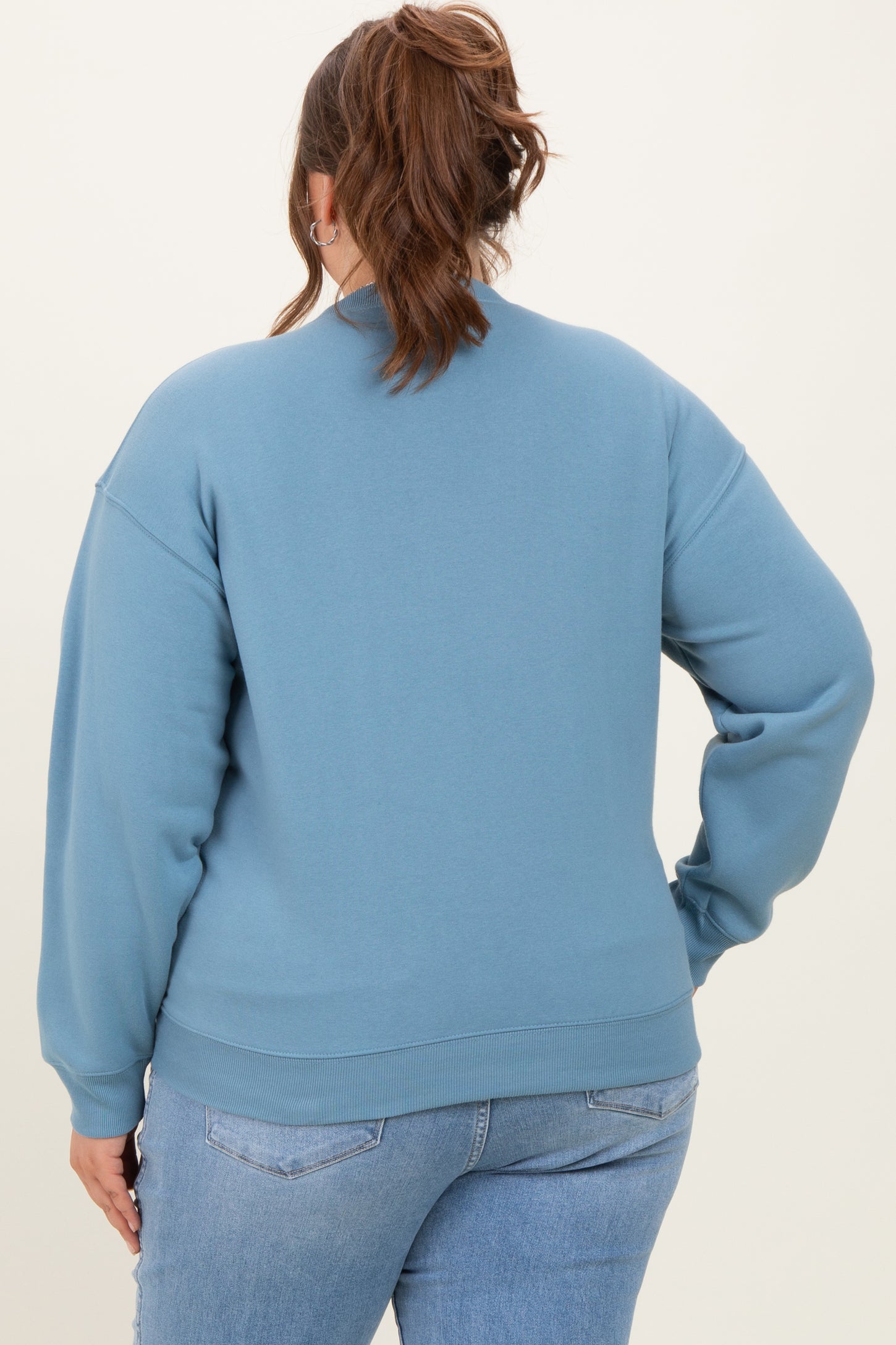 woman wearing a light blue maternity plus sweatshirt, showing a relaxed fit and soft fabric from the back