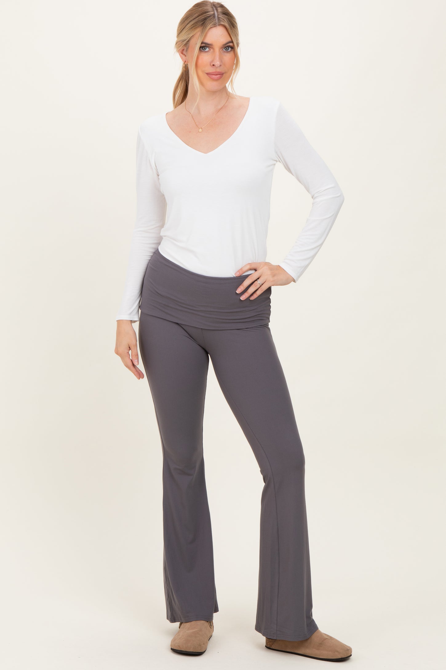 woman wearing a white long sleeve v-neck top and gray flared yoga pants