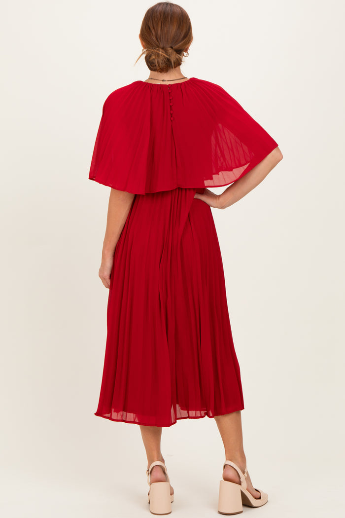 woman wearing a back view of a red pleated midi dress with a cape style top and buttons down the back