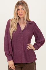 woman wearing a burgundy pullover top with a collar and balloon sleeves, styled casually
