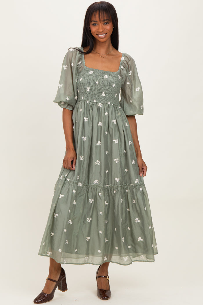 woman wearing a light green maxi dress with floral embroidery and puff sleeves