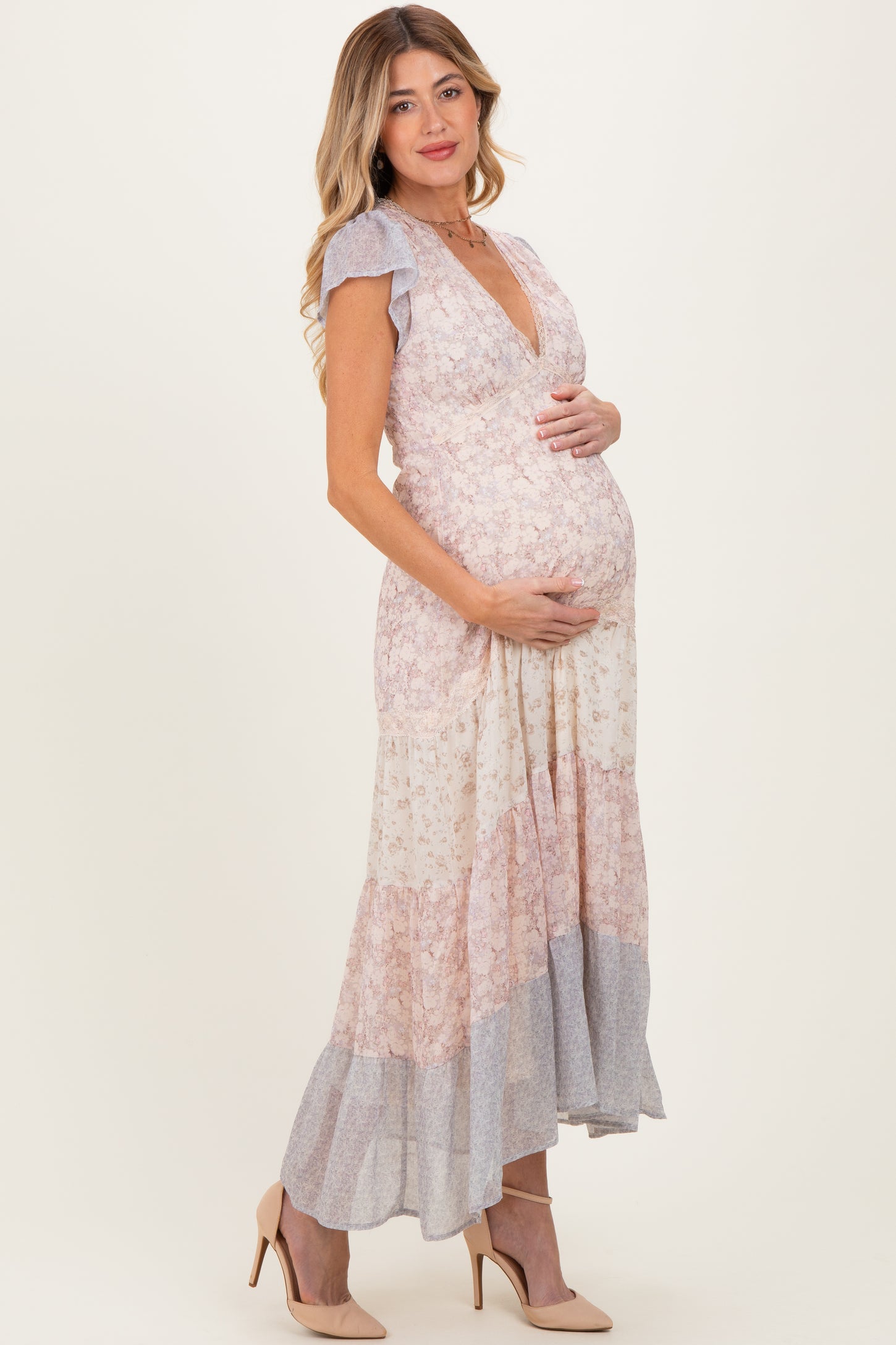 woman wearing a floral print maternity maxi dress with a deep v-neck and ruffled sleeves, showing her baby bump