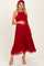 woman wearing a red pleated maternity dress and holding her baby bump