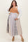 woman wearing a color-blocked maternity plus dress with a brown top and patterned skirt, holding her baby bump