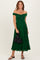 woman wearing a green off-the-shoulder pleated dress and holding a black purse