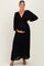 woman wearing a black maxi maternity dress with a deep v-neck and gathered bodice, holding her baby bump