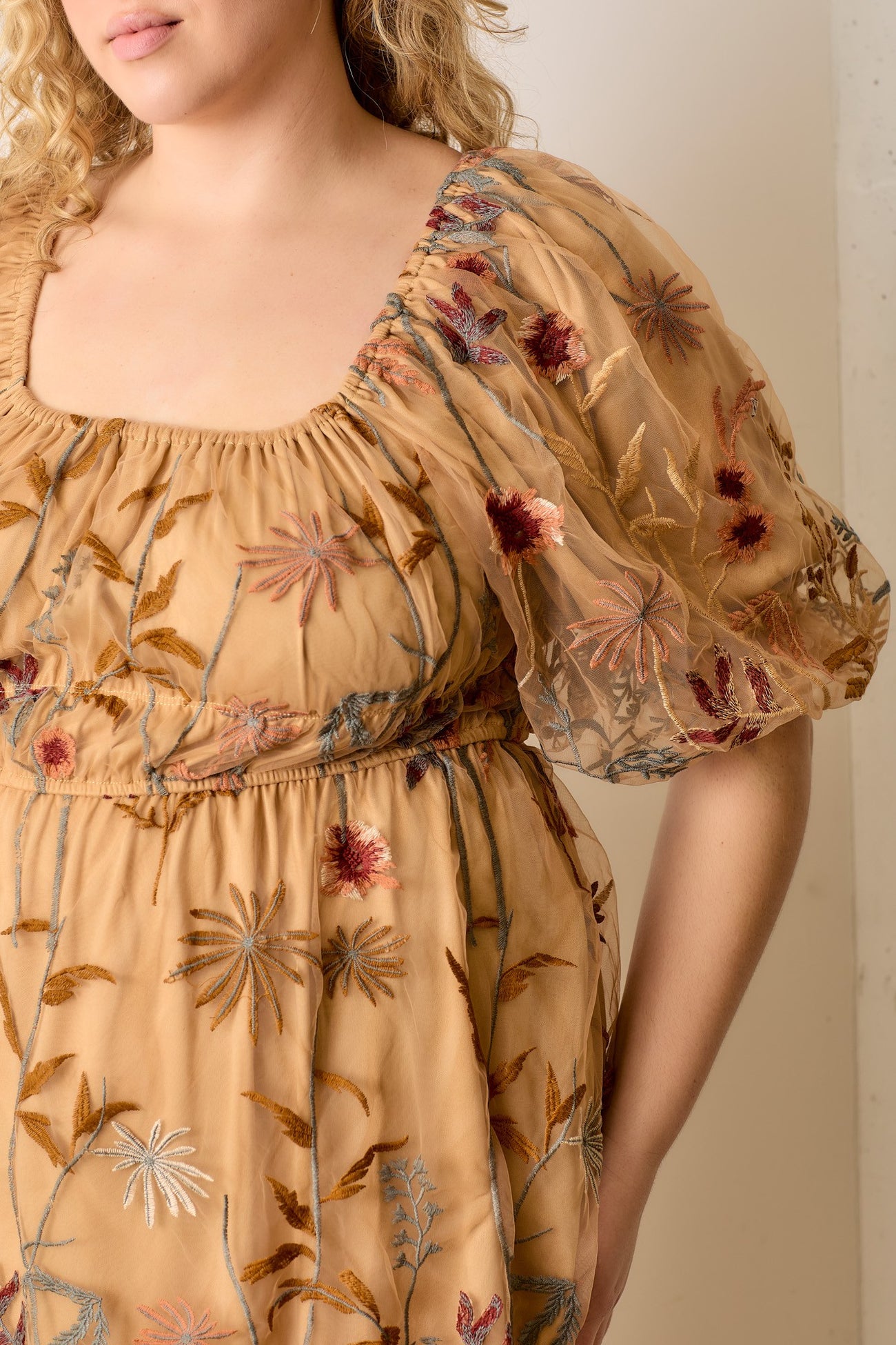 plus size woman wearing a mustard yellow floral embroidered dress with puff sleeves and a square neckline