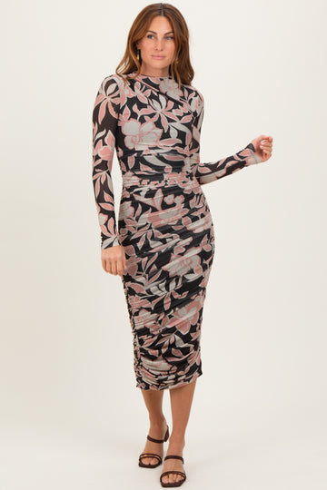woman wearing a floral print long sleeve bodycon dress with ruching details and a midi length