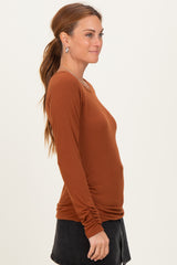 woman wearing a rust long sleeve ribbed top styled with a black skirt