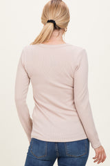 woman wearing a light pink long sleeve ribbed top, viewed from the back, paired with blue jeans
