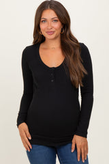 woman wearing a black long sleeve scoop neck maternity top with button detailing and a fitted style
