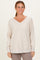 woman wearing a light beige oversized v-neck sweatshirt with a front pocket and relaxed fit