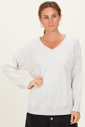 woman wearing a light gray v-neck sweatshirt with a pocket and relaxed fit, styled with black jeans