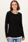 woman wearing a black long sleeve top with a white scalloped hem over a white shirt, smiling against a light background