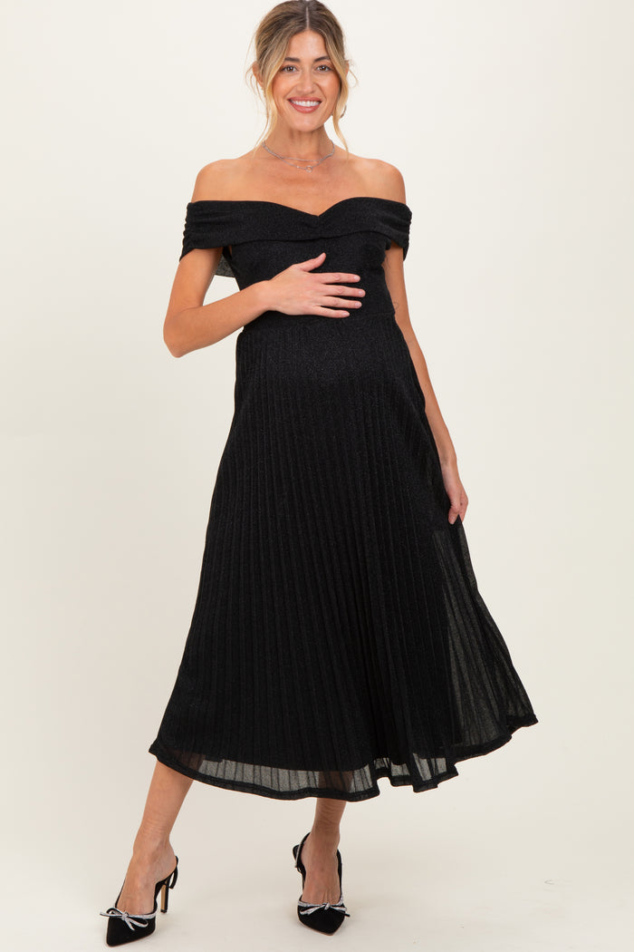 woman wearing a black off-the-shoulder maternity dress with pleated detail and holding her baby bump