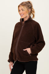 woman wearing a brown maternity fleece jacket with a zip front and side pockets, showing a baby bump