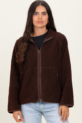woman wearing a chocolate brown fuzzy zip-up jacket over a black top and light blue jeans