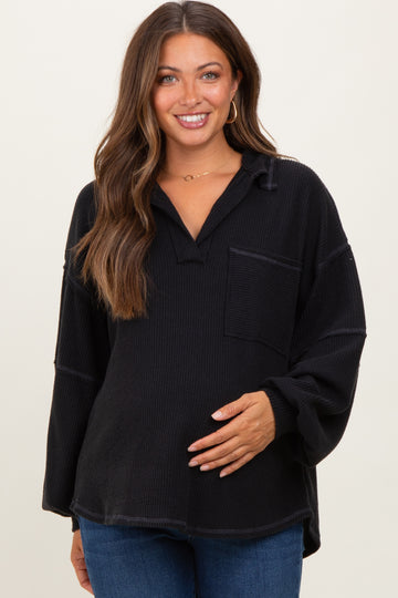 woman wearing a black maternity top with a loose fit and long sleeves, holding her baby bump
