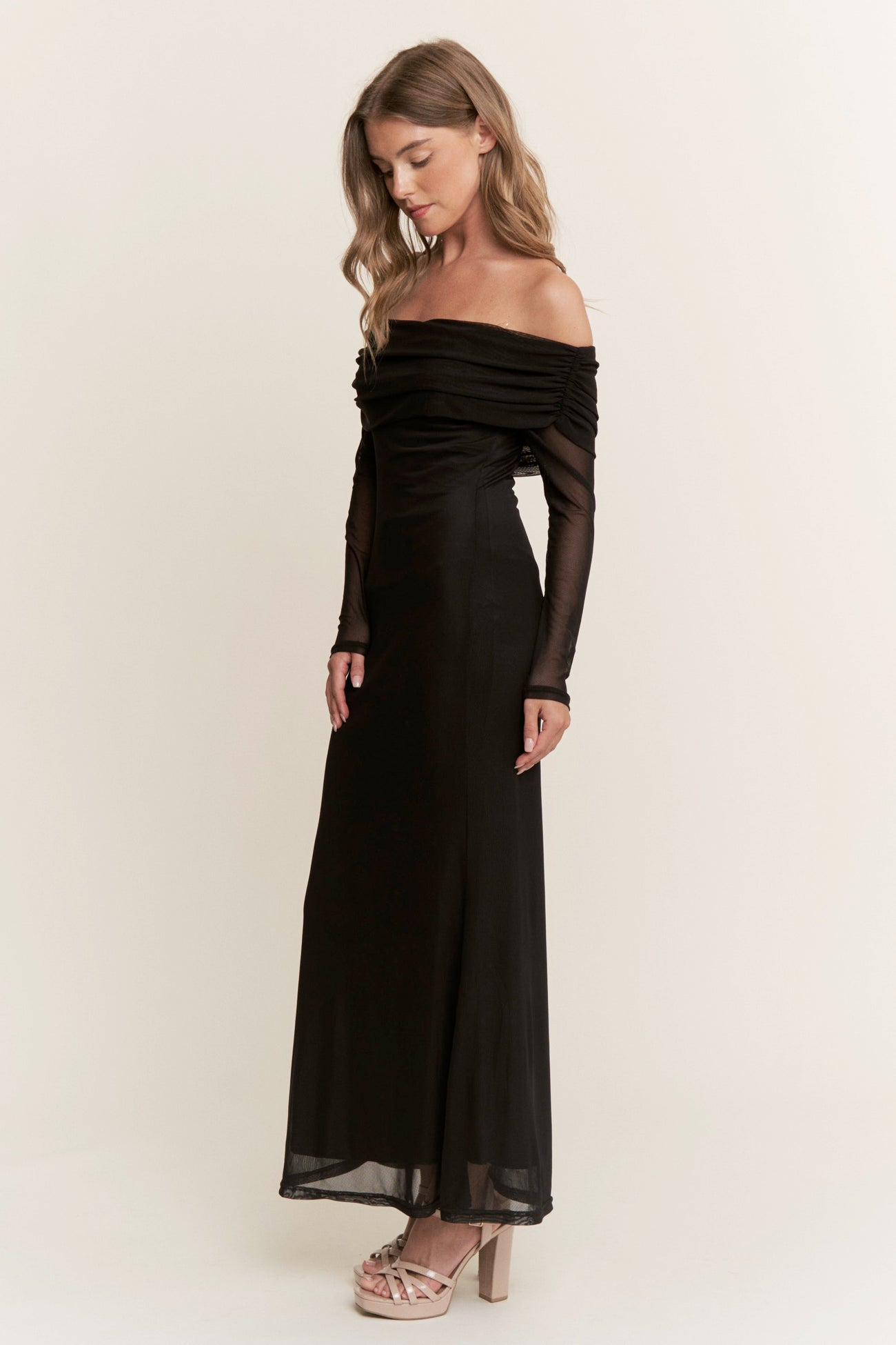woman wearing a black off-shoulder long evening dress with sheer long sleeves and a fitted silhouette