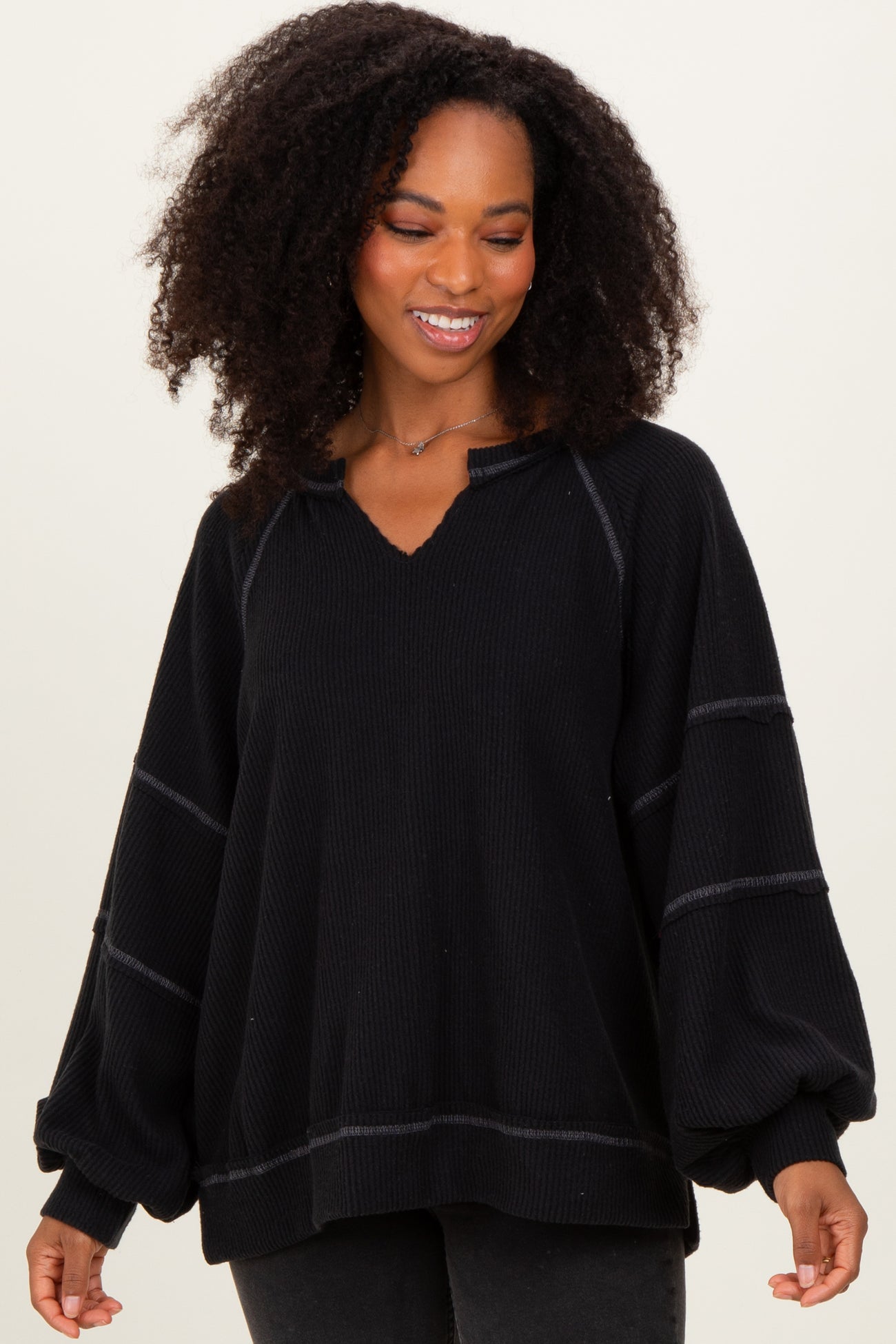 woman wearing a black oversized long sleeve pullover top with a v-neck and relaxed fit