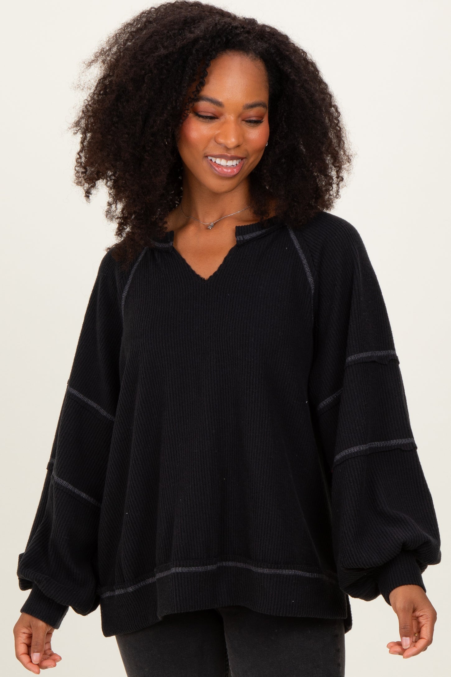 woman wearing a black oversized long sleeve pullover top with a v-neck and relaxed fit