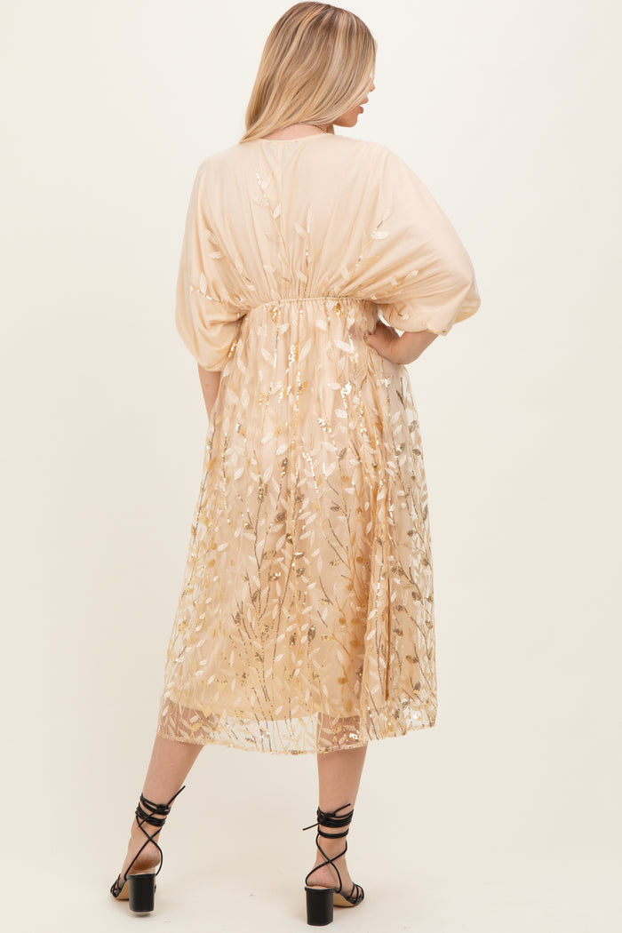 woman wearing a beige floral embroidered maxi dress with a flowy silhouette and tied waist, shown from the back