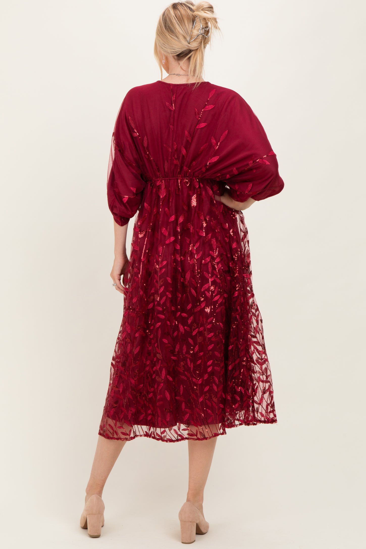 woman wearing a burgundy embroidered maxi dress with sheer overlay and balloon sleeves, seen from the back