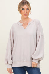 woman wearing a light beige oversized sweater with a v-neck and balloon sleeves, styled with blue jeans