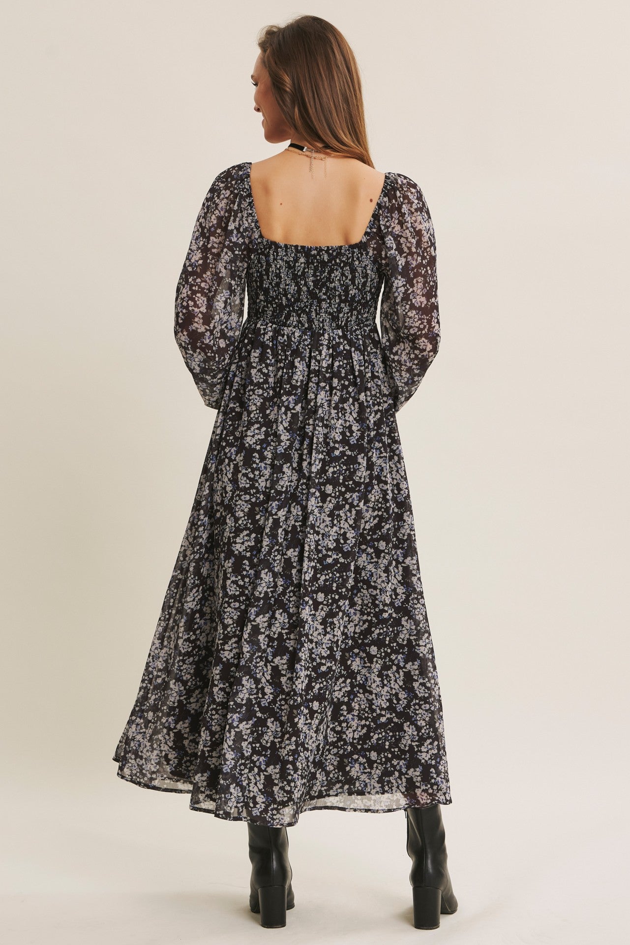 woman wearing a black floral maxi dress with puff sleeves, showcasing a smocked back detail