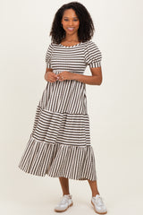 woman wearing a black and white striped tiered midi dress with short puff sleeves and white sneakers