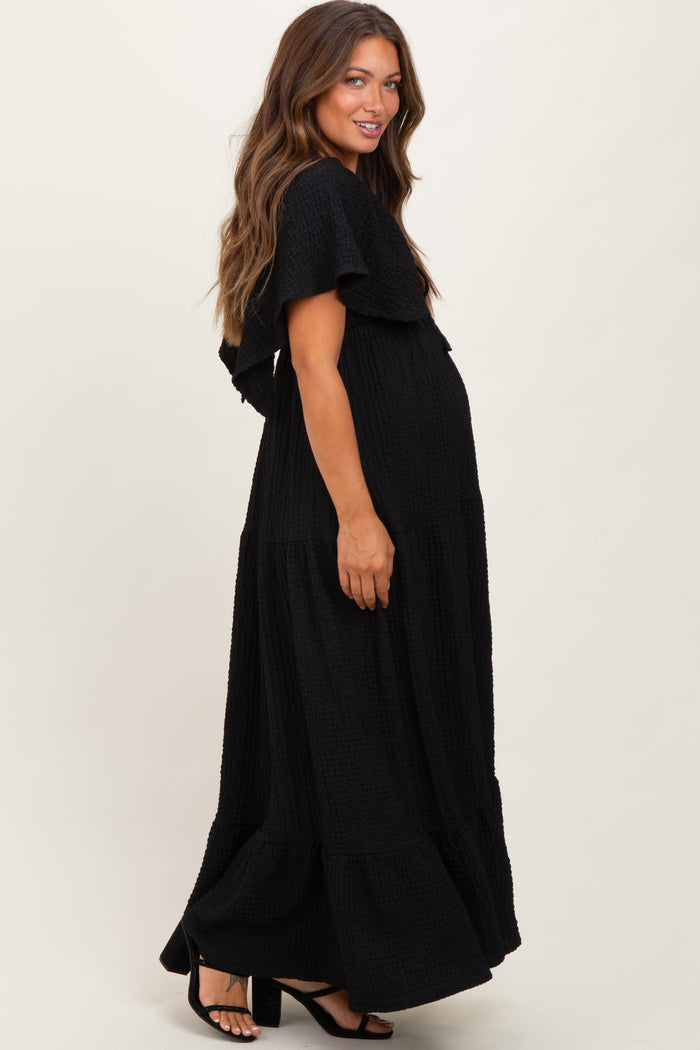 woman wearing a black maternity maxi dress with tiered ruffles and a visible baby bump