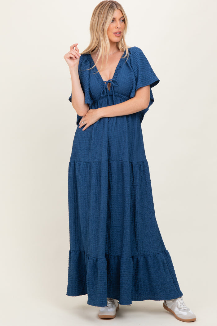 woman wearing a navy blue maxi dress with short flutter sleeves and a tie front detail