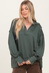 woman wearing a dark green oversized sweatshirt with a collared neckline and relaxed sleeves