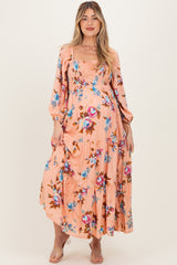 woman wearing a blush floral maternity maxi dress with puff sleeves and a smocked bodice, displaying her baby bump