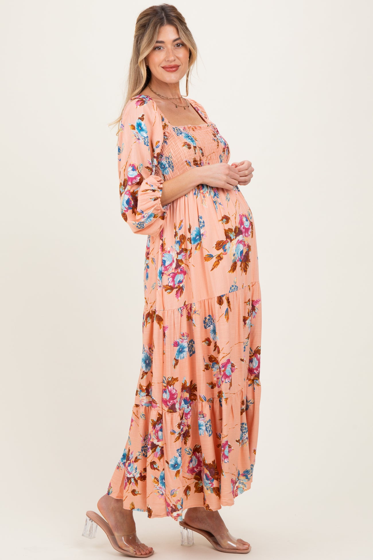 woman wearing a pink floral maternity maxi dress with puff sleeves and a visible baby bump