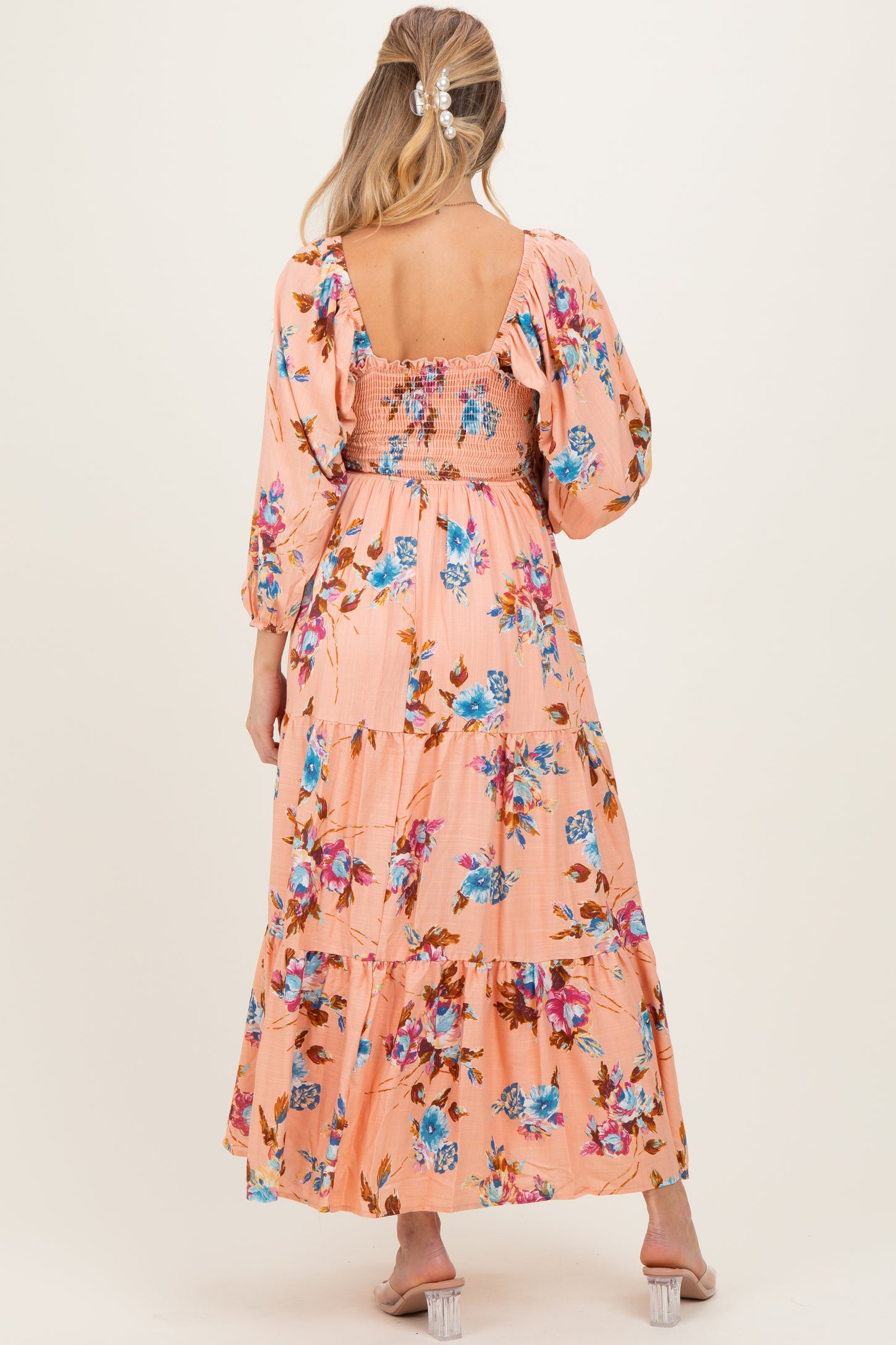 woman wearing a peach floral maternity maxi dress with puff sleeves and a smocked bodice, showing a baby bump from the back