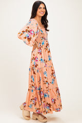 woman wearing a pink floral maxi dress with bell sleeves and a tiered skirt, smiling while posing sideways