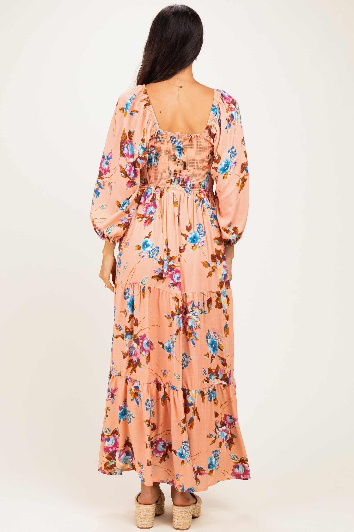 woman wearing a floral patterned maxi dress in peach with puff sleeves and a smocked back