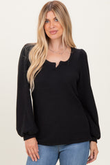 woman wearing a black puff sleeve sweater with a v-neck and ribbed texture, paired with blue jeans