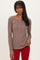 woman wearing a taupe long sleeve henley top with button details and paired with red pants