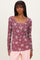 woman wearing a burgundy floral long sleeve scoop neck top with button details and ribbed texture