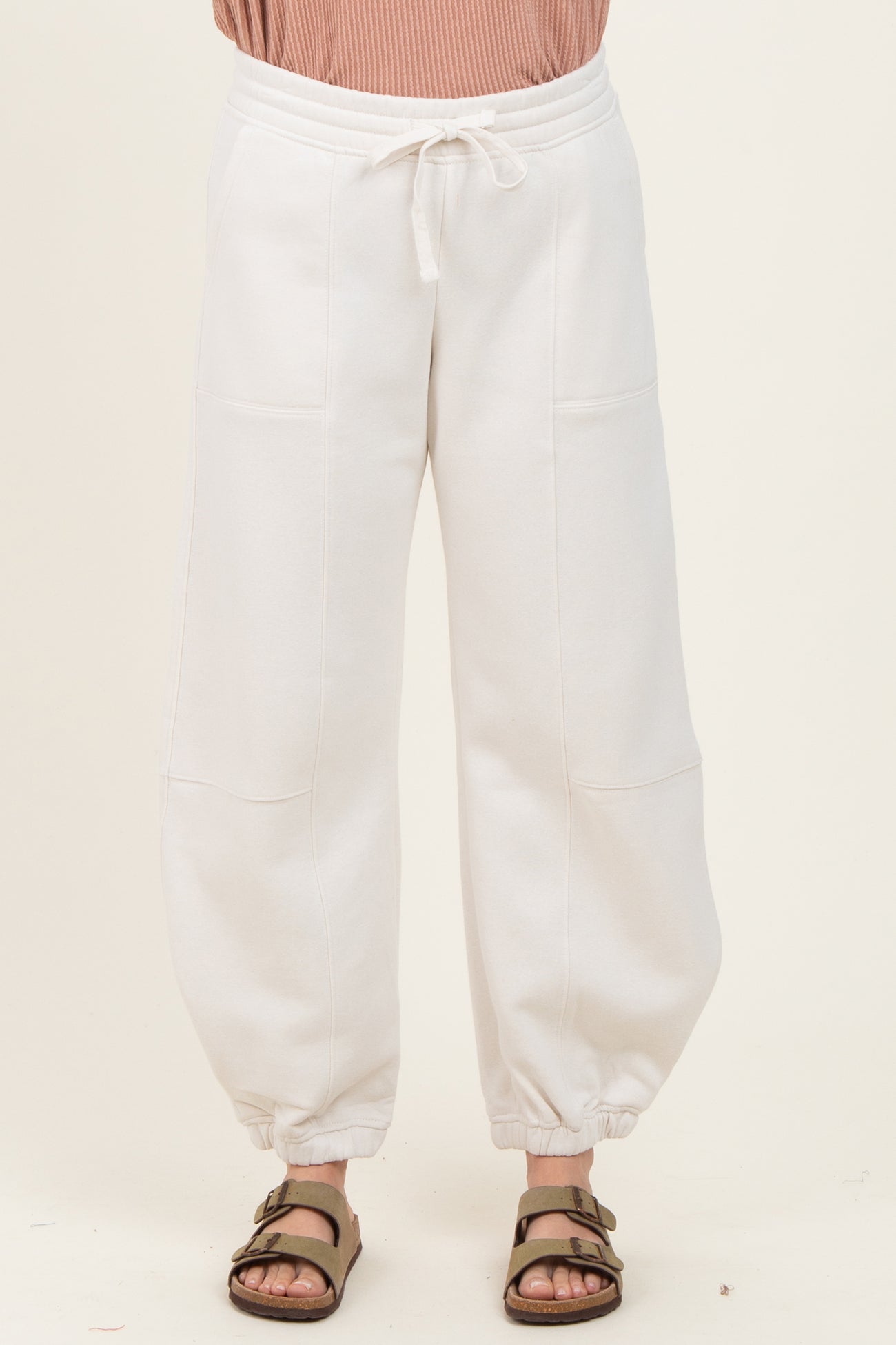 woman wearing cream-colored wide-leg sweatpants with elastic cuffs and drawstring waist