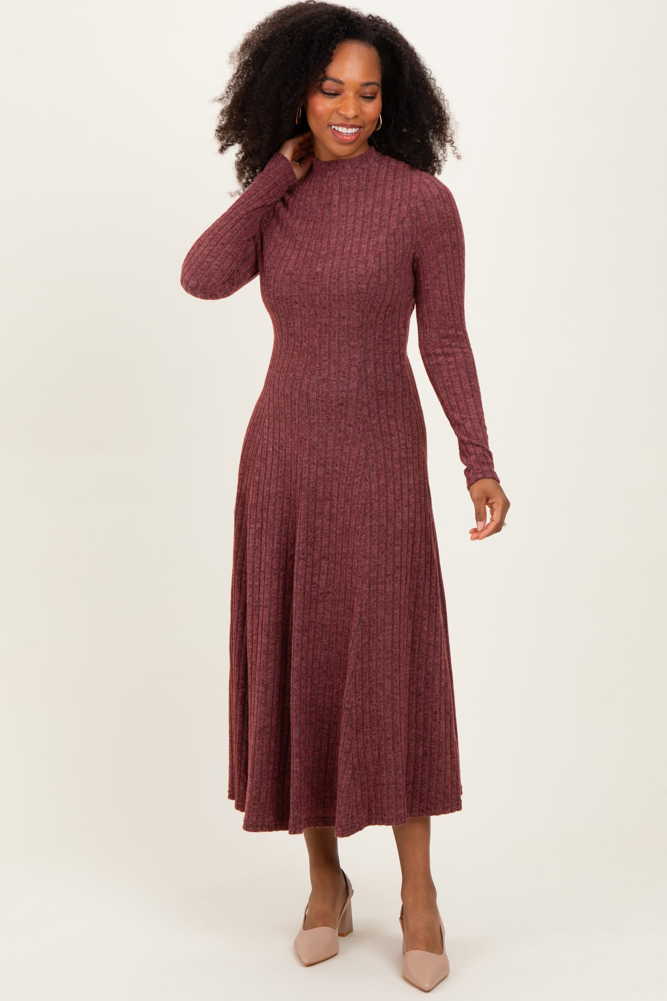 woman wearing a burgundy ribbed long sleeve midi dress and beige heels