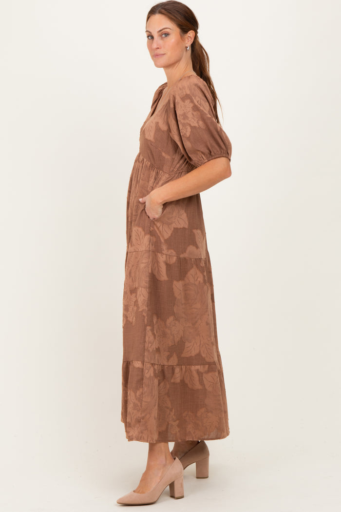 woman wearing a brown floral maxi dress with puff sleeves and pockets, standing sideways