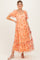 woman wearing a floral maternity dress in peach with puff sleeves and a tiered skirt, showcasing her baby bump
