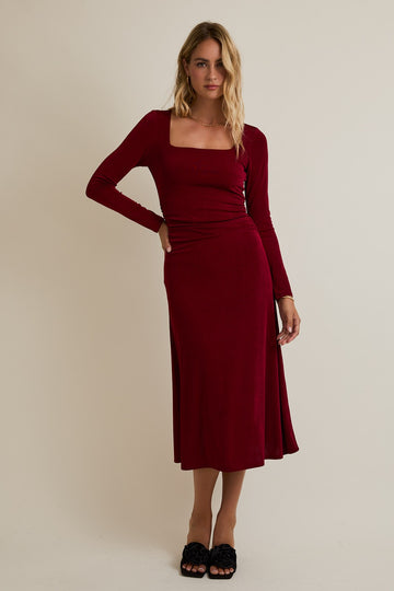 woman wearing a burgundy long sleeve midi dress with a square neckline and a side split