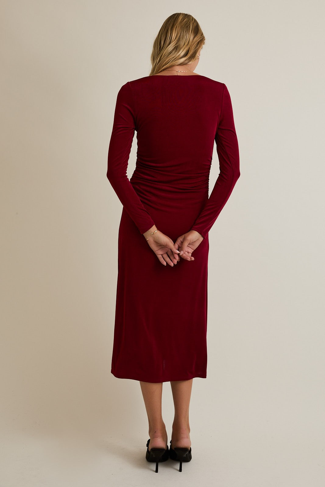 woman wearing a burgundy long sleeve midi dress with ruching details at the back
