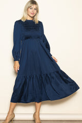 woman wearing a navy blue long sleeve smocked midi dress with a tiered skirt and puff sleeves