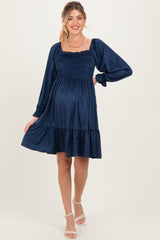 woman wearing a navy blue maternity dress with smocked bodice and flared skirt, showing off her baby bump