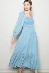 woman wearing a light blue smocked bodice long sleeve maxi dress with a tiered ruffle hem